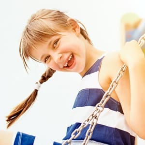 Young girl smiling outdoors swinging