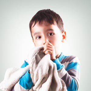 Young child holding a blanket to his face