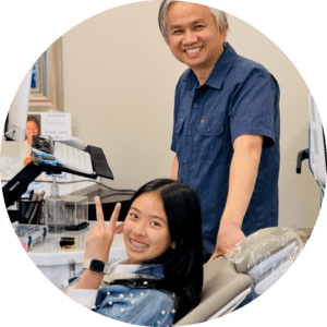 A man and woman comfortably seated in dental chairs, with dental equipment visible in the background.